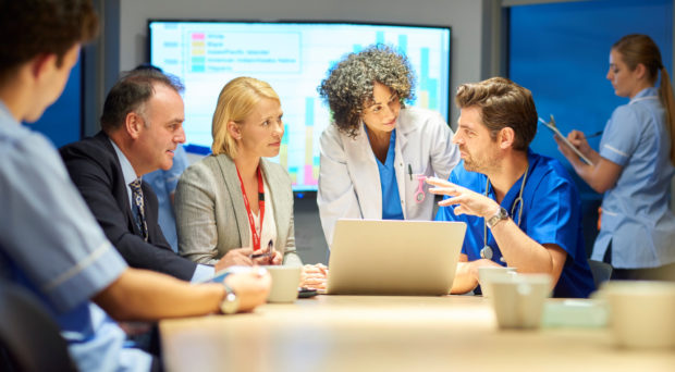 a mixed group of healthcare professional and business people meet around a conference table