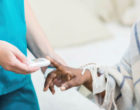An image of a nurse testing the blood sugar of a patient using a handheld device.
